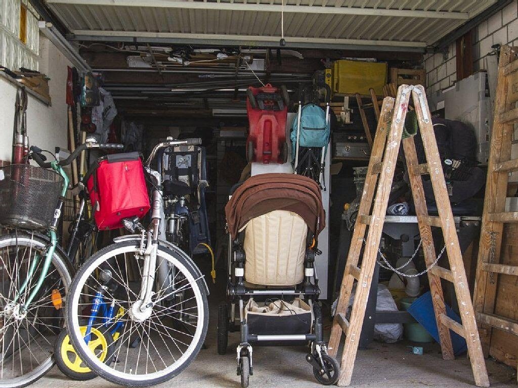 Chaotische Garage mit Fahrrädern, Kinderwagen, Leiter und Lagergut.