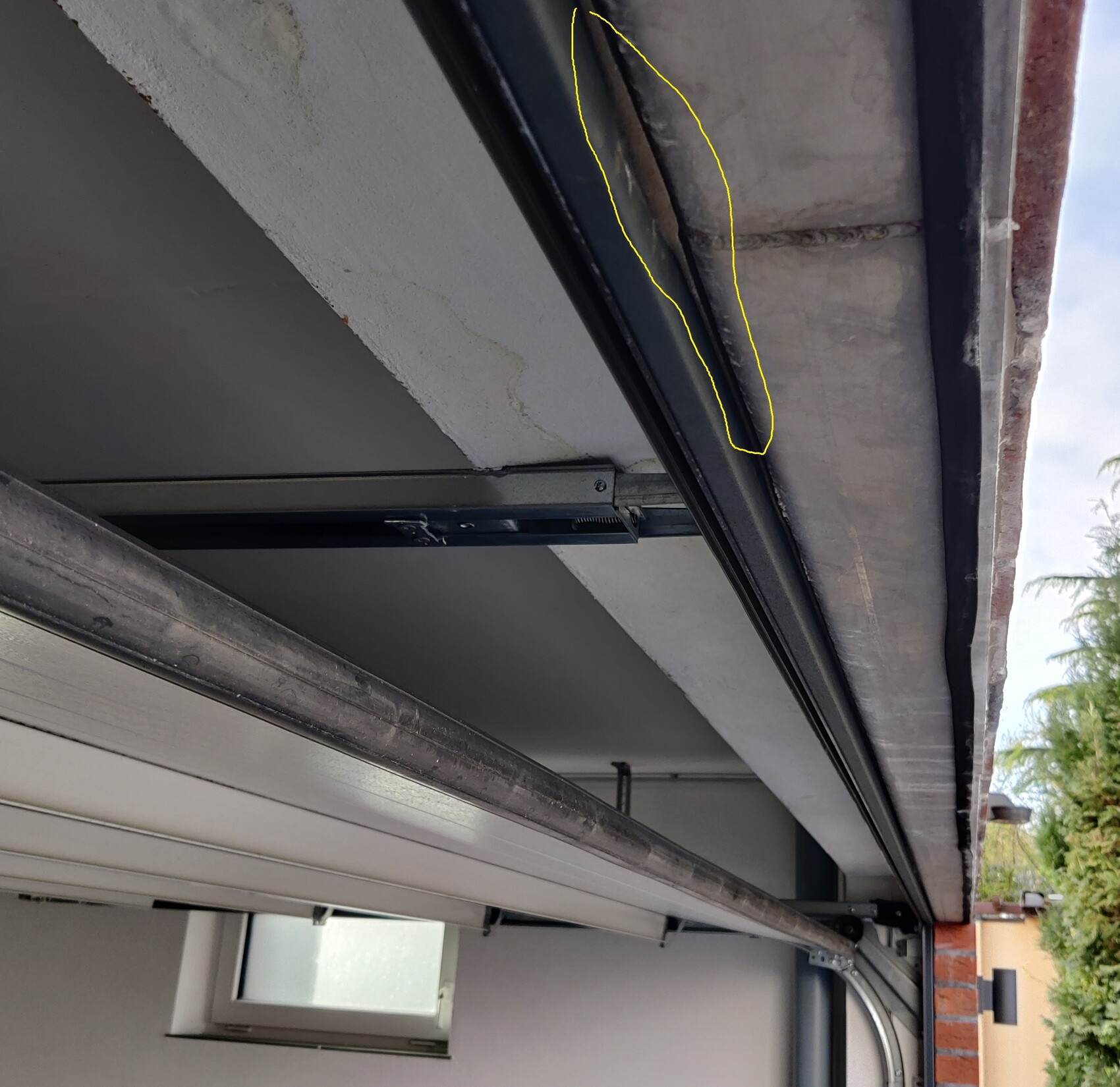 Unterseite einer Garage mit Rollladenführung; gelb markierte Rissstelle am Dachrand.