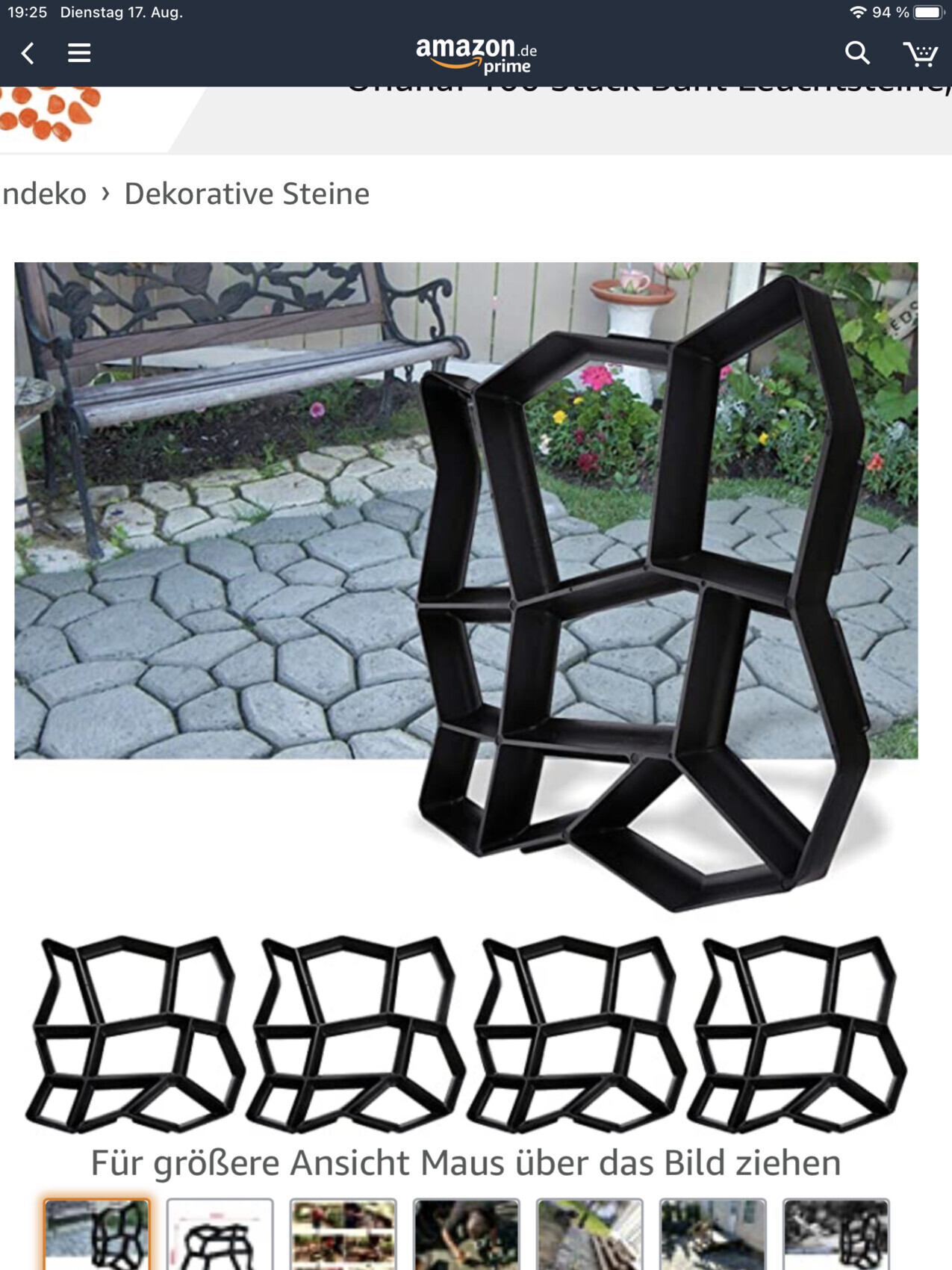 Schwarze geometrische Skulptur aus verbundenen Polygonrahmen auf einem gepflasterten Gartenvorplatz.