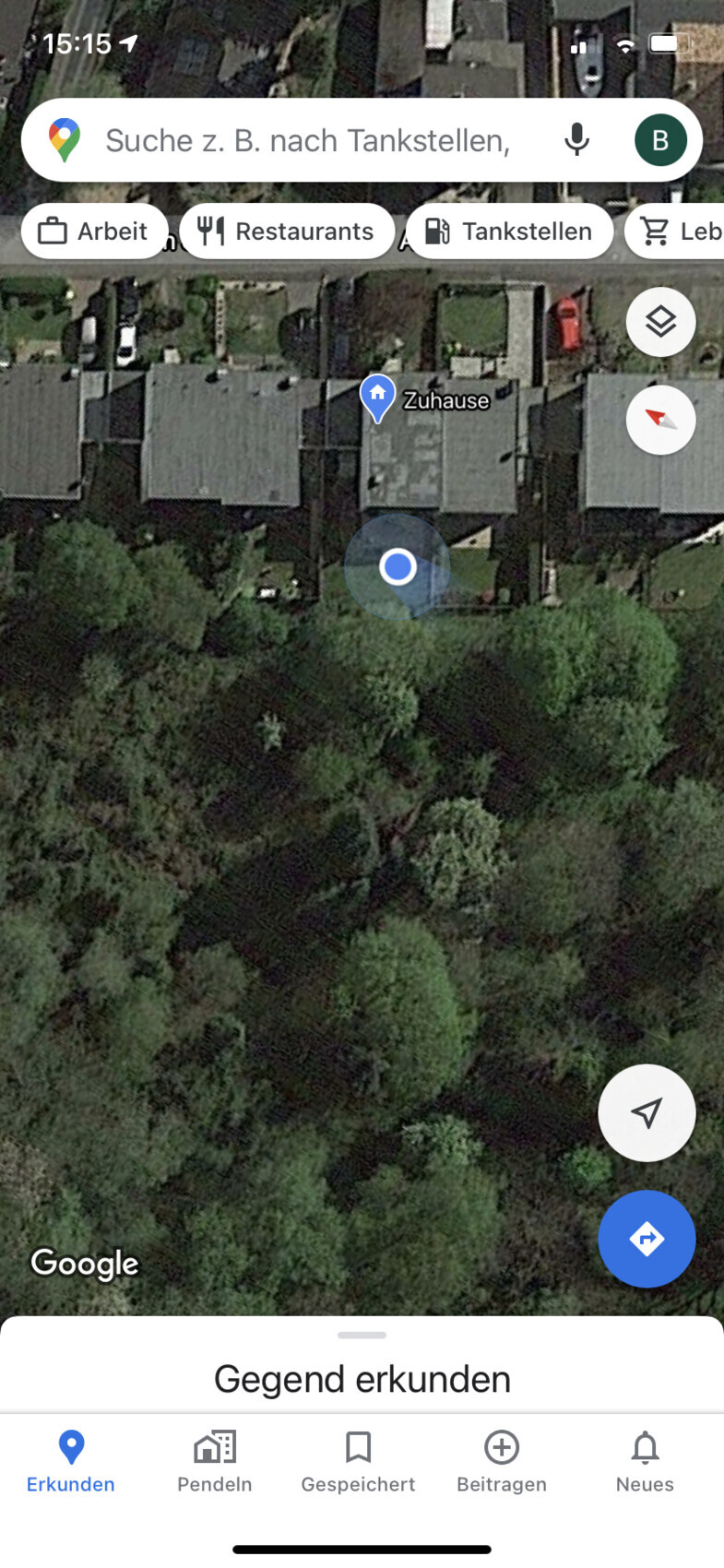 Satellitenbild eines Wohnviertels mit Häusern, grünem Wald unten und blauem Marker 'Zuhause'.