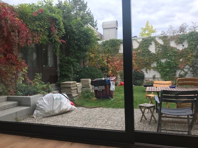 Garten mit Terrasse hinter Glas-Schiebetür, Gartenmöbel und Bau-Materialien