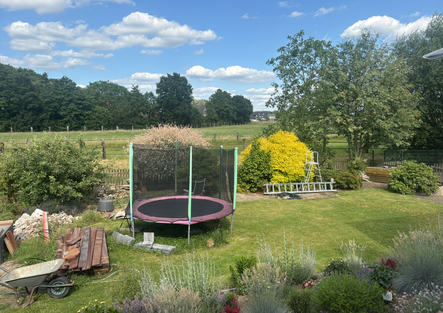 garten-trampolin-im-garten-landschaft-mit-pflanzen-und-bau-materialien.png