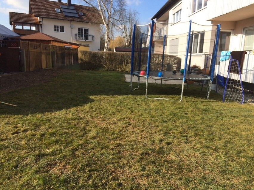 Garten mit Trampolin im Hinterhof eines Wohnhauses, Spielgerät und Rasenfläche