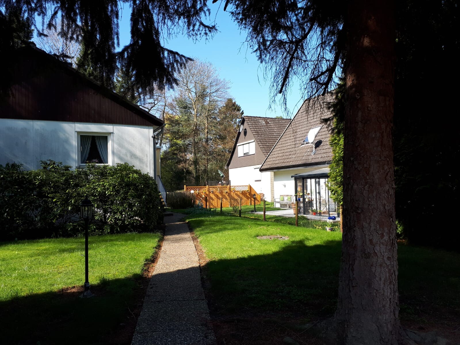 Blick auf Gartenweg zwischen zwei Wohnhäusern mit Bäumen und Hecken