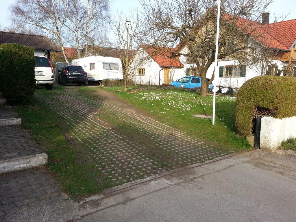 Außenansicht eines Wohnviertels: Zufahrt, Garten und geparkte Autos