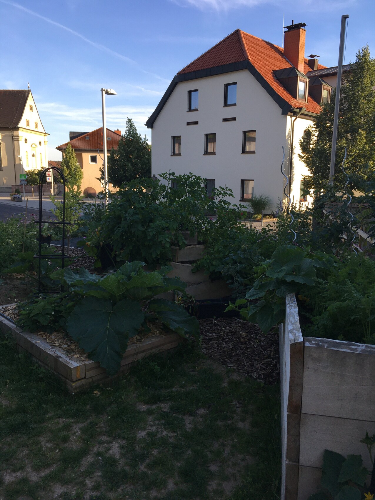Außenansicht eines Mehrfamilienhauses mit rotem Dach und Gartenbeeten im Vordergrund
