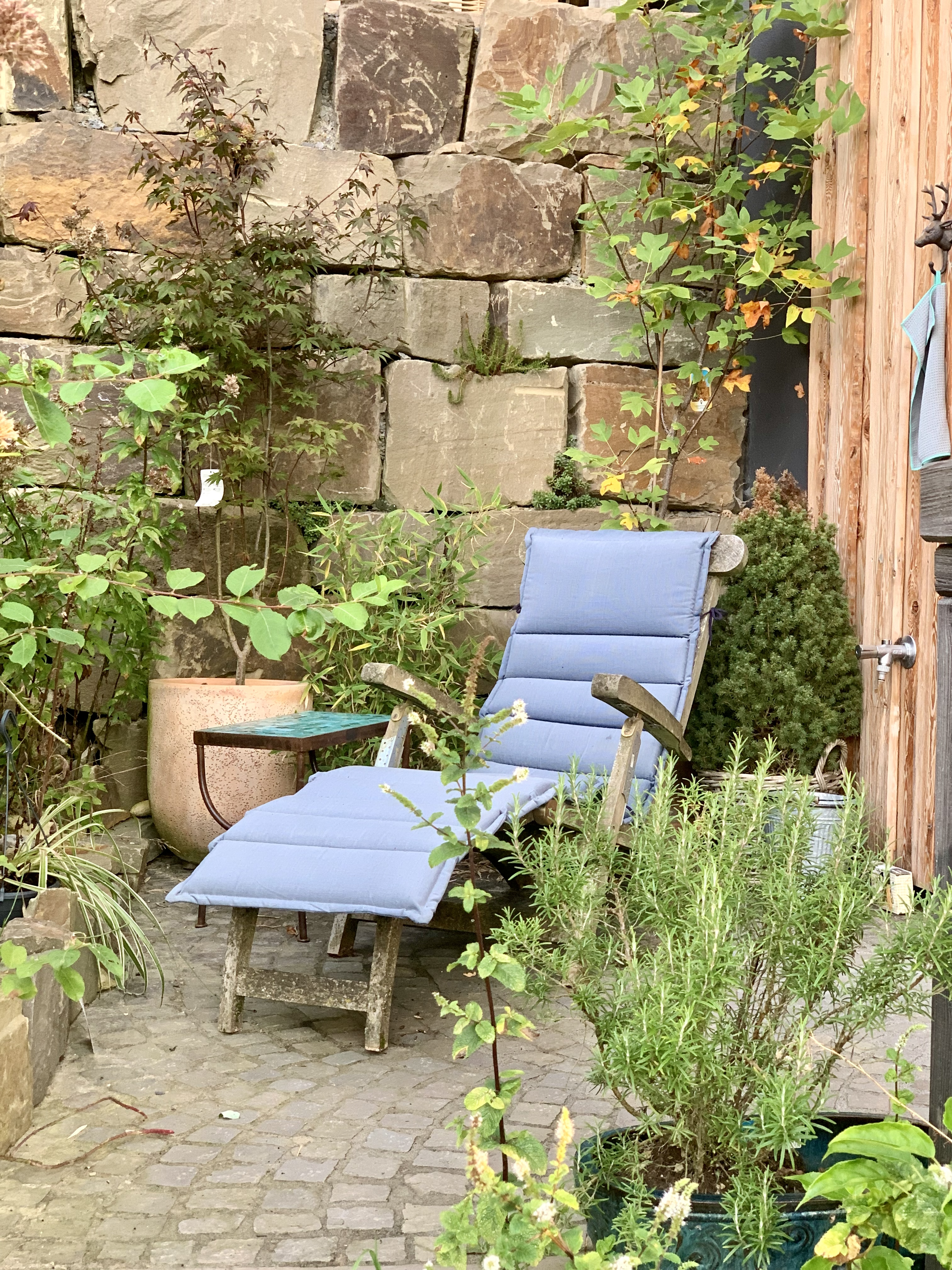 gartenterrasse-loungesessel-hellblau-pflanzen-steinwand.png