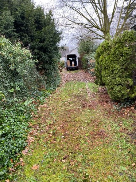 gartenweg-zwischen-gruenen-hecken-und-laubbaeumen-trailer-im-hintergrund.jpg