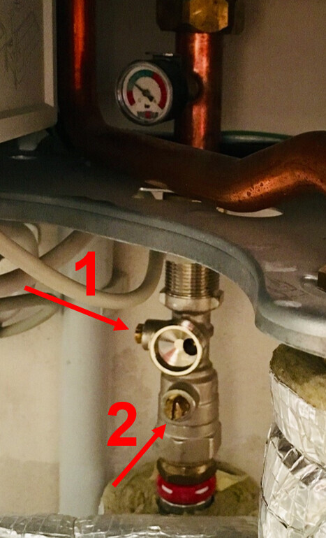 Messing-Druckventil mit Manometer unter Kupferrohr; Pfeile markieren 1 und 2.