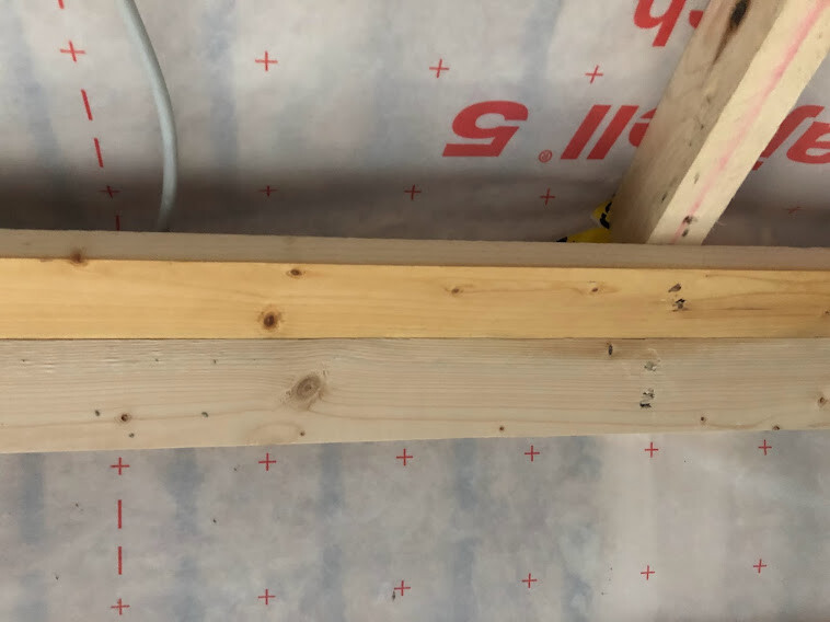 Bau-Holzbalken über Plastikfolie mit roten Pluszeichen in einer Baustellenszene.