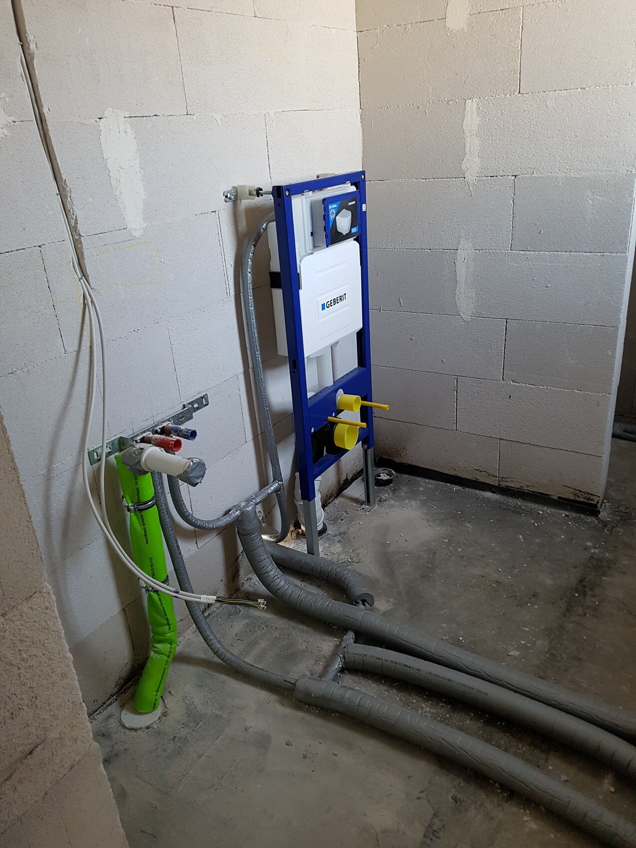 Geberit Spülrahmen-WC im Rohbau, blaue Rahmenkonstruktion und sichtbare Rohre.