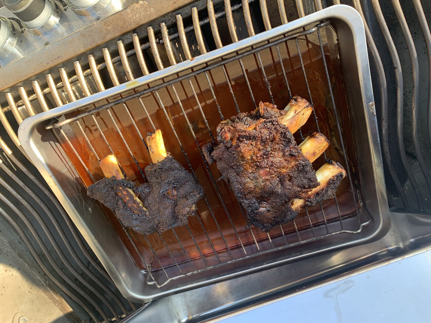 Gegrillte Rippchen mit dunkler Kruste liegen in einer Bratrinne im Ofen