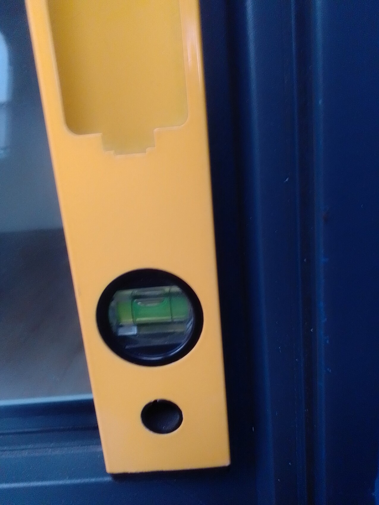 Nahaufnahme einer gelben Wasserwaage an blauem Türrahmen