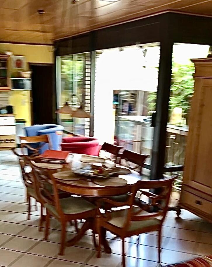 Runder Holztisch mit Stühlen in offenem Küchen- und Essbereich und Glastüren nach draußen