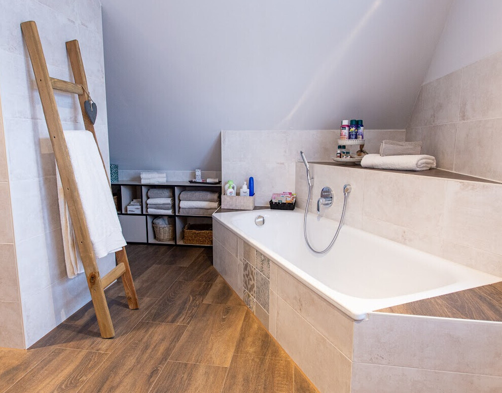 Modernes Badezimmer mit freistehender Badewanne, Holzfliesen und Handtuchregal.