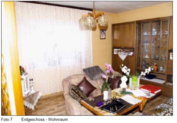Wohnzimmer mit Sofa, Couchtisch, Orchideen, Vitrine und gelben Wänden mit Vorhängen.