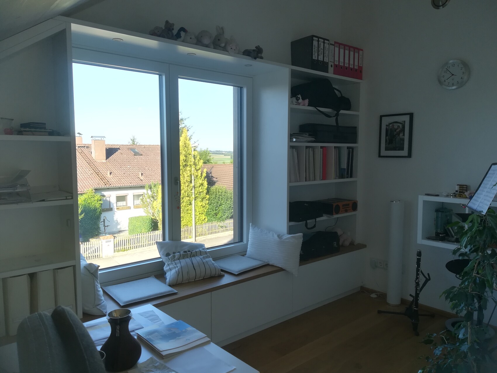 Helles Wohnzimmer mit Fensterbank, Bücherregal, Pflanzen und Musikständer