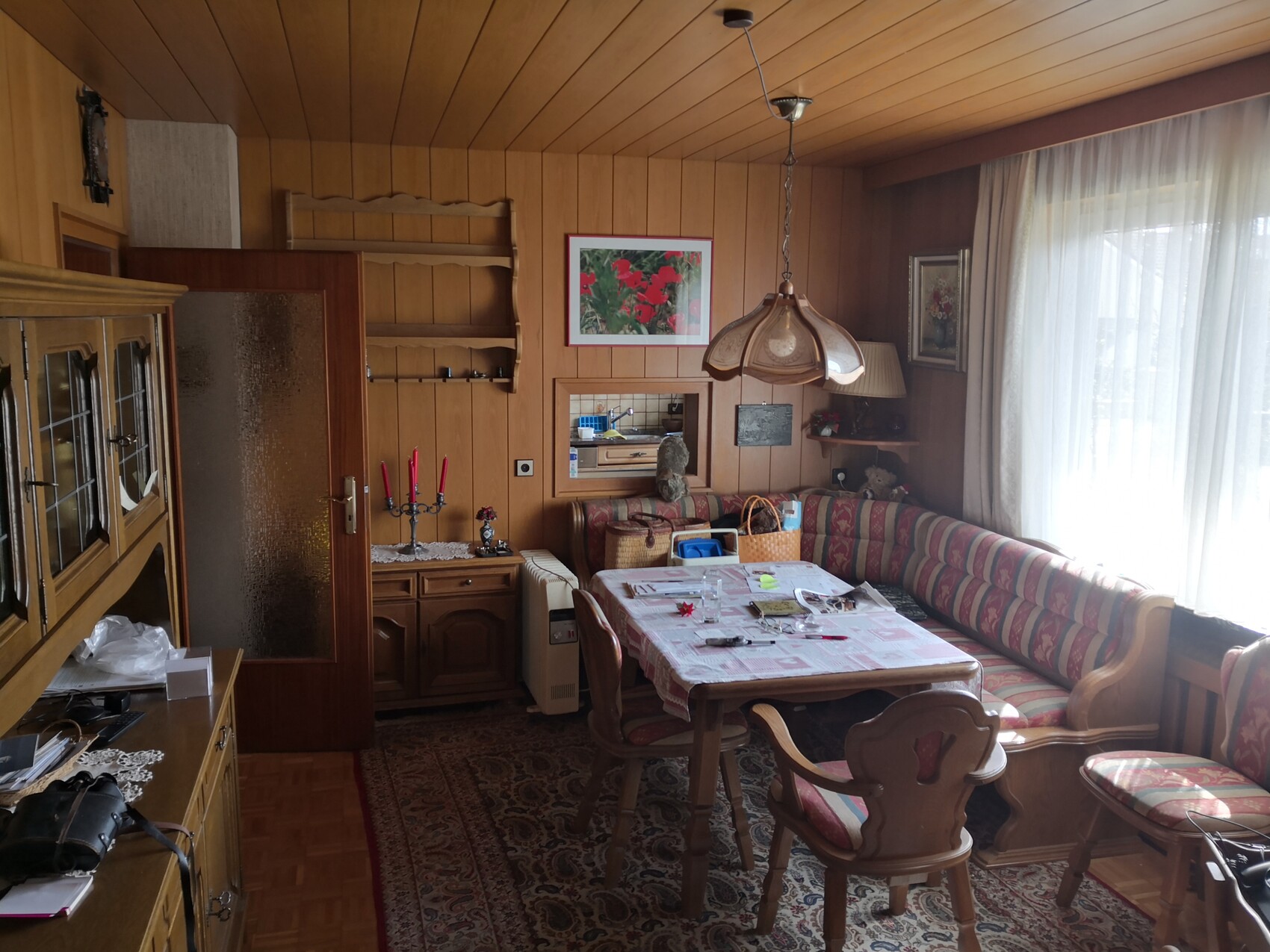 Holzverkleideter Essbereich mit Esstisch, Eckbank, Deckenlampe und Fensterfront.