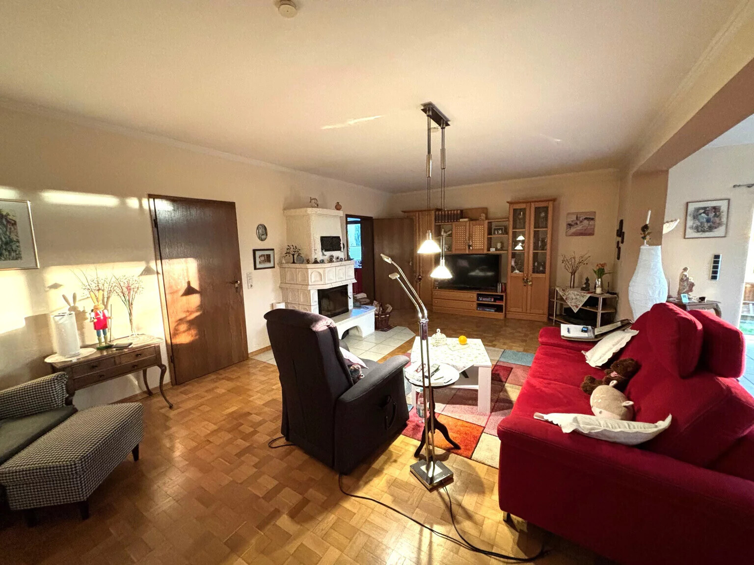 Gemütliches Wohnzimmer mit rotem Sofa, braunem Sessel, Kamin und TV-Möbel.