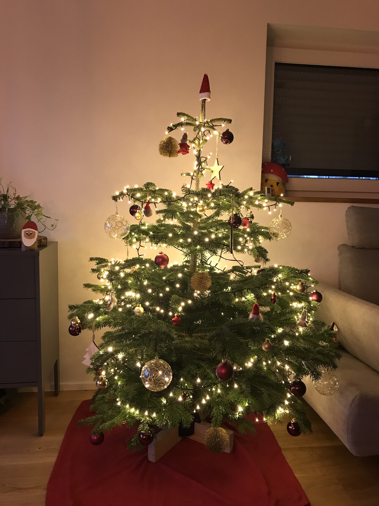 Kleiner geschmückter Weihnachtsbaum mit Lichterketten, Kugeln und Stern im Wohnzimmer.