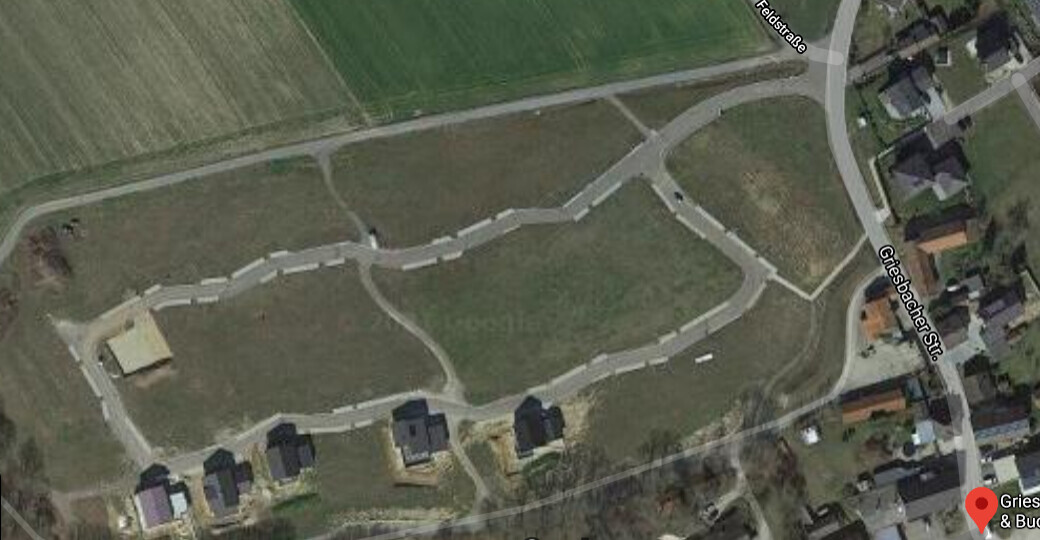Luftbild eines offenen Feldes mit einem Netz aus Wegen und einigen Häusern an der Straße.