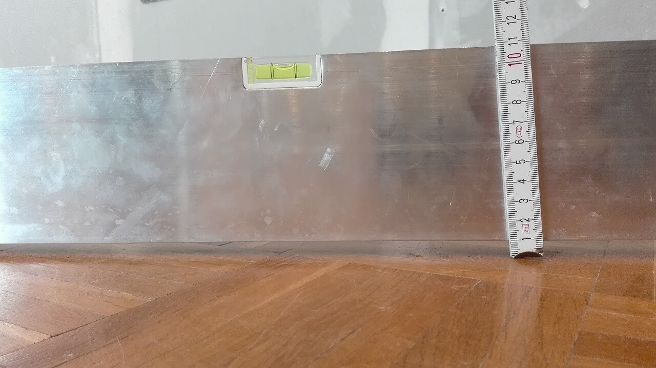 Detailaufnahme einer glanzenden Metallverkleidung mit Wasserwaage und Massband im Innenausbau