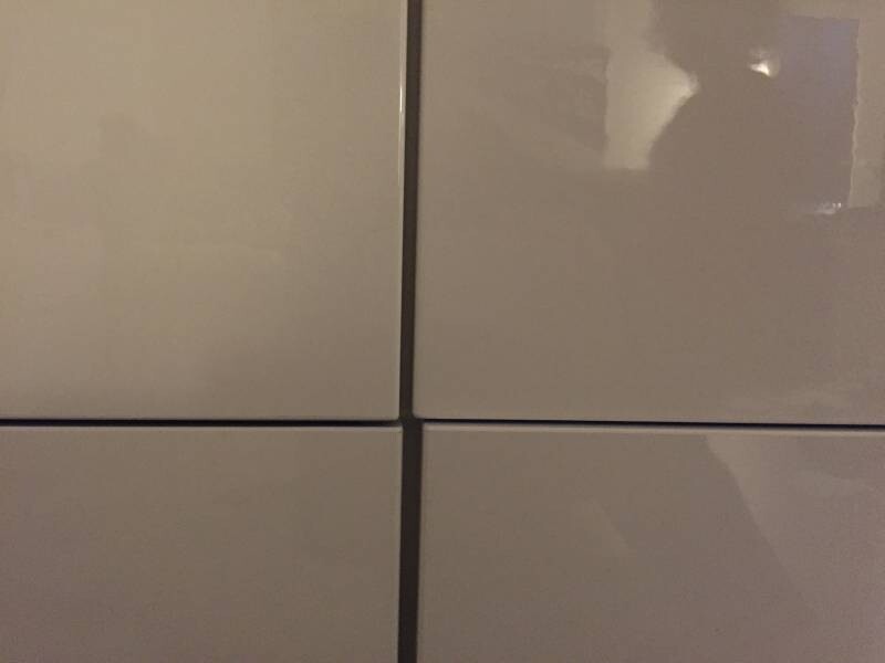 Vier beige quadratische Fliesen in 2x2-Anordnung mit Fugen und glänzenden Oberflächen.