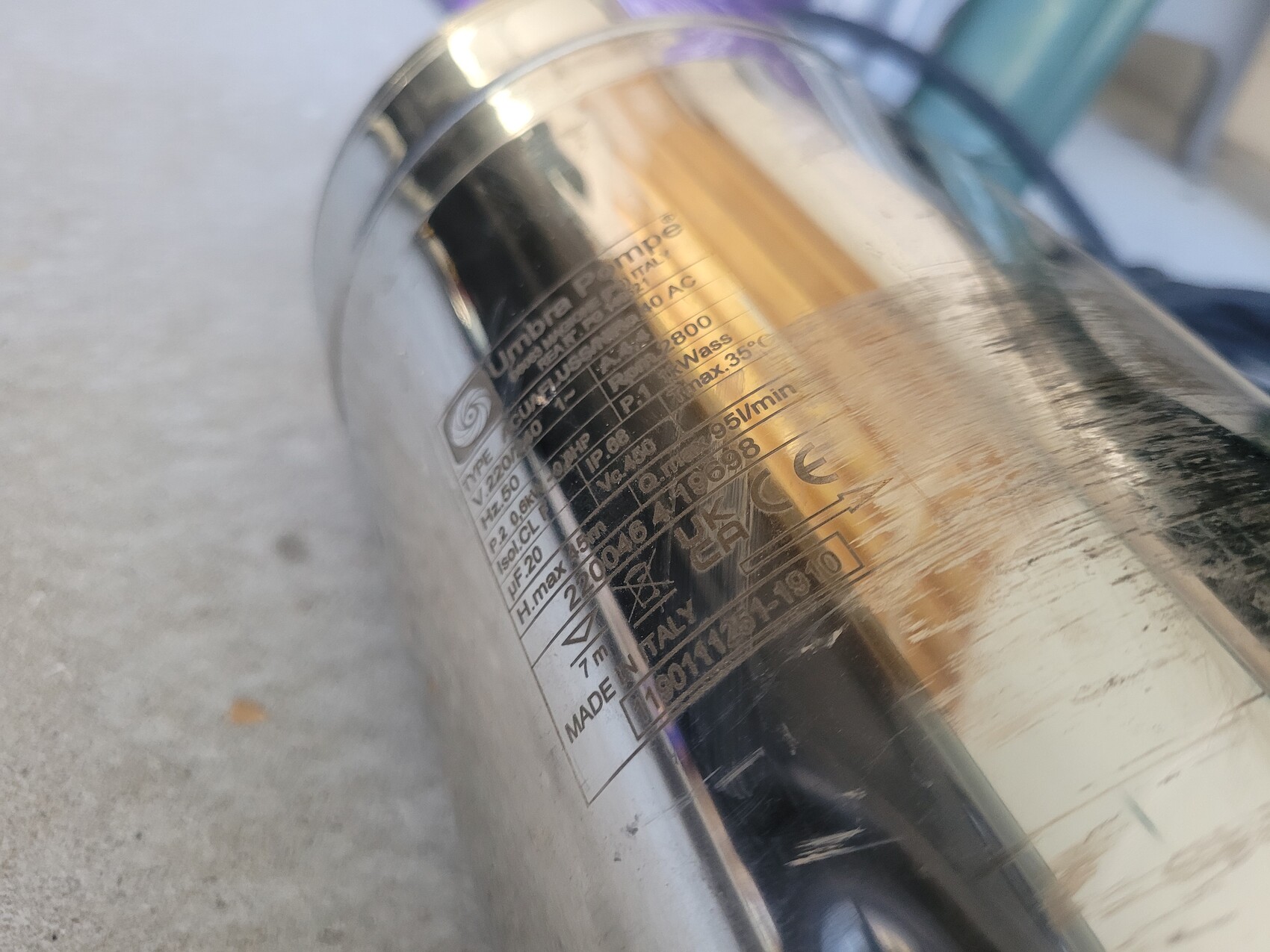 Nahaufnahme eines glänzenden Metallrohrs mit Aufdruck und Reflexionen.