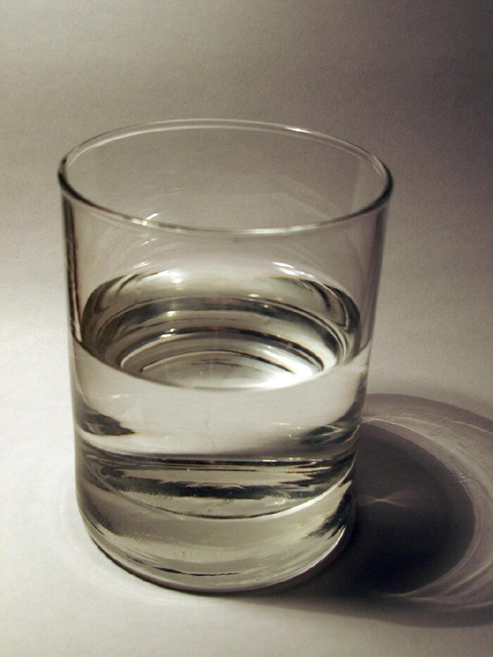 Klares Glas Wasser auf heller Unterlage mit Schattenwurf