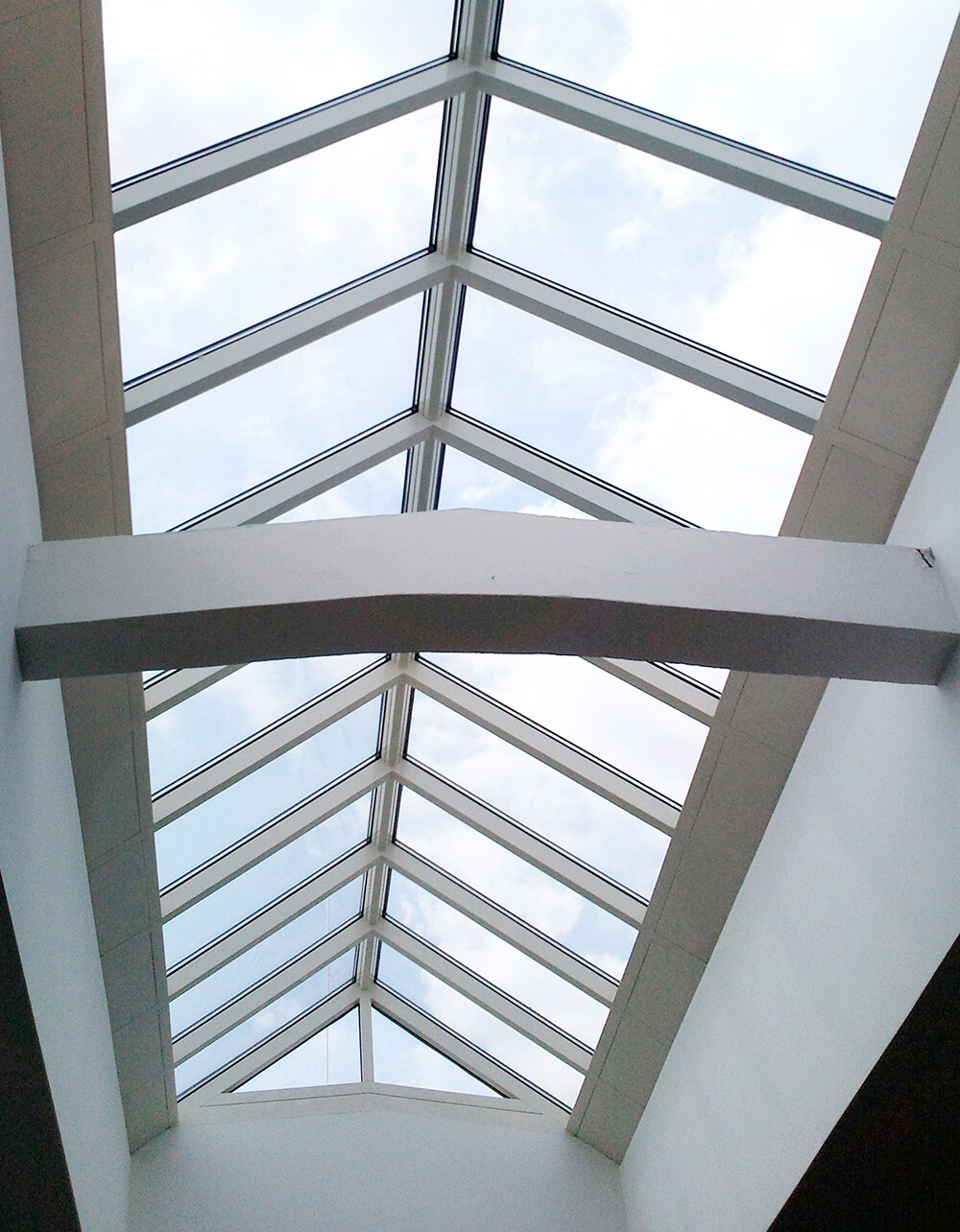 Innenansicht eines Glasdach-Atriums mit weißen Tragwerkstrukturen und Blick nach draußen