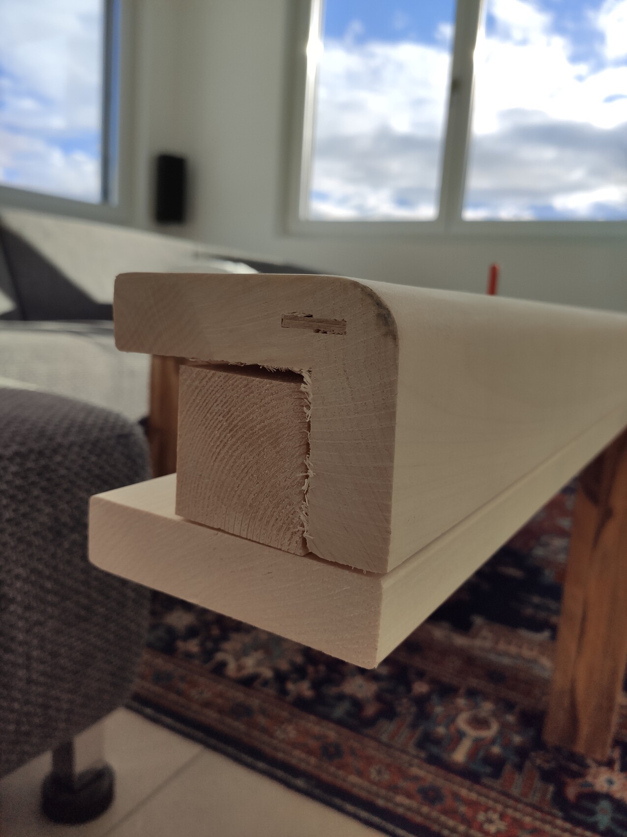 Nahaufnahme eines hellen Holzteils mit einer Nut/Öffnung, Möbelprojekt, Wohnzimmer im Hintergrund.
