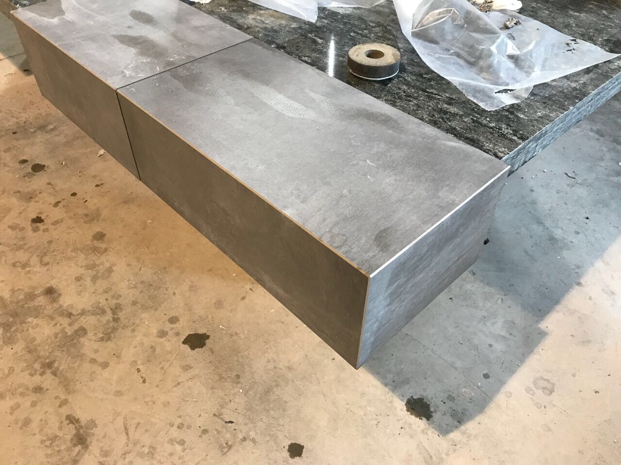 Granitplatten-Arbeitsplatte in Bauwerkstatt, Metallkante und Schutzfolie zu sehen.