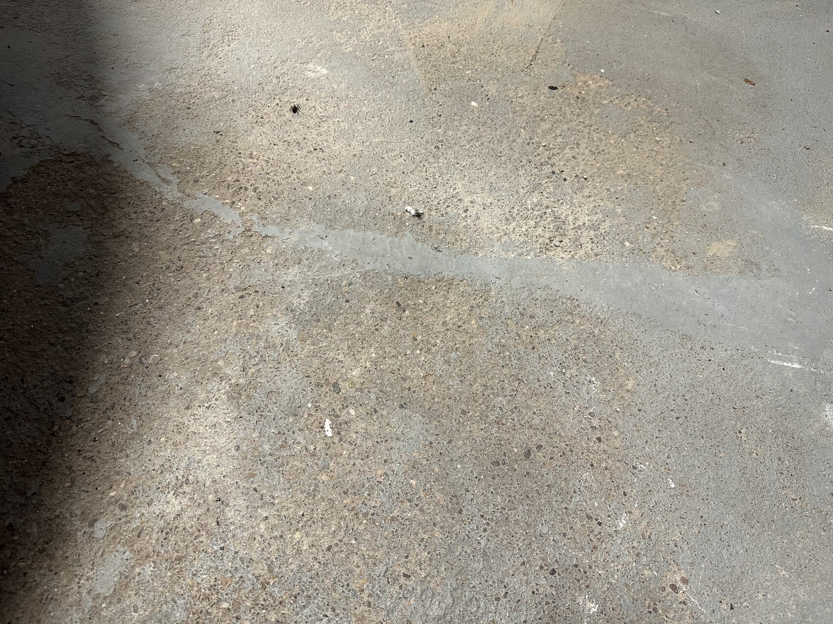 Nahaufnahme einer rauen Betonoberfläche mit Verfärbungen, Flecken und Kieskörnern.