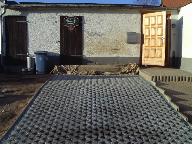Außenansicht eines Gebäudes mit langer rutschfester Metallrampe vor Türen und Treppe.