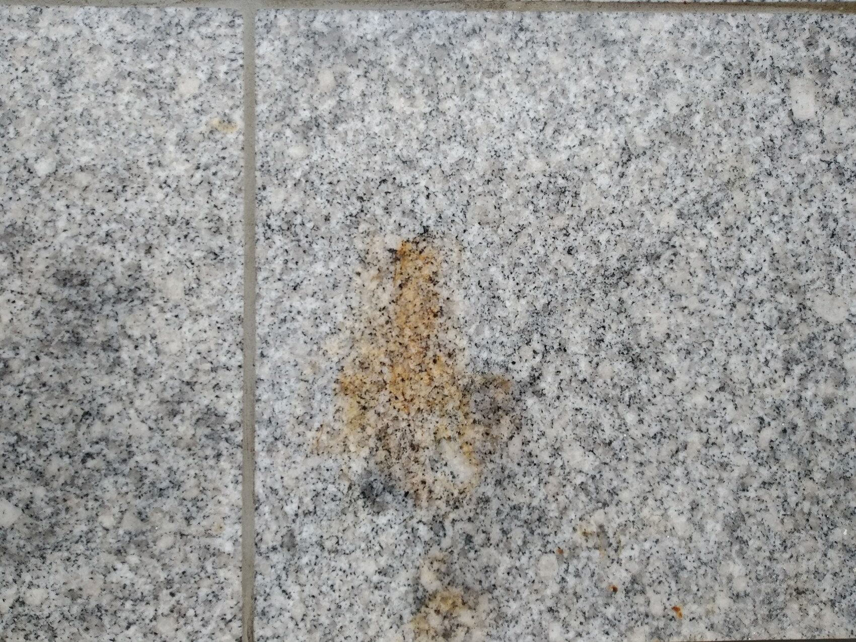 Grau gemusterte Granitfliesen mit einer braunen Verfärbung in der Mitte.