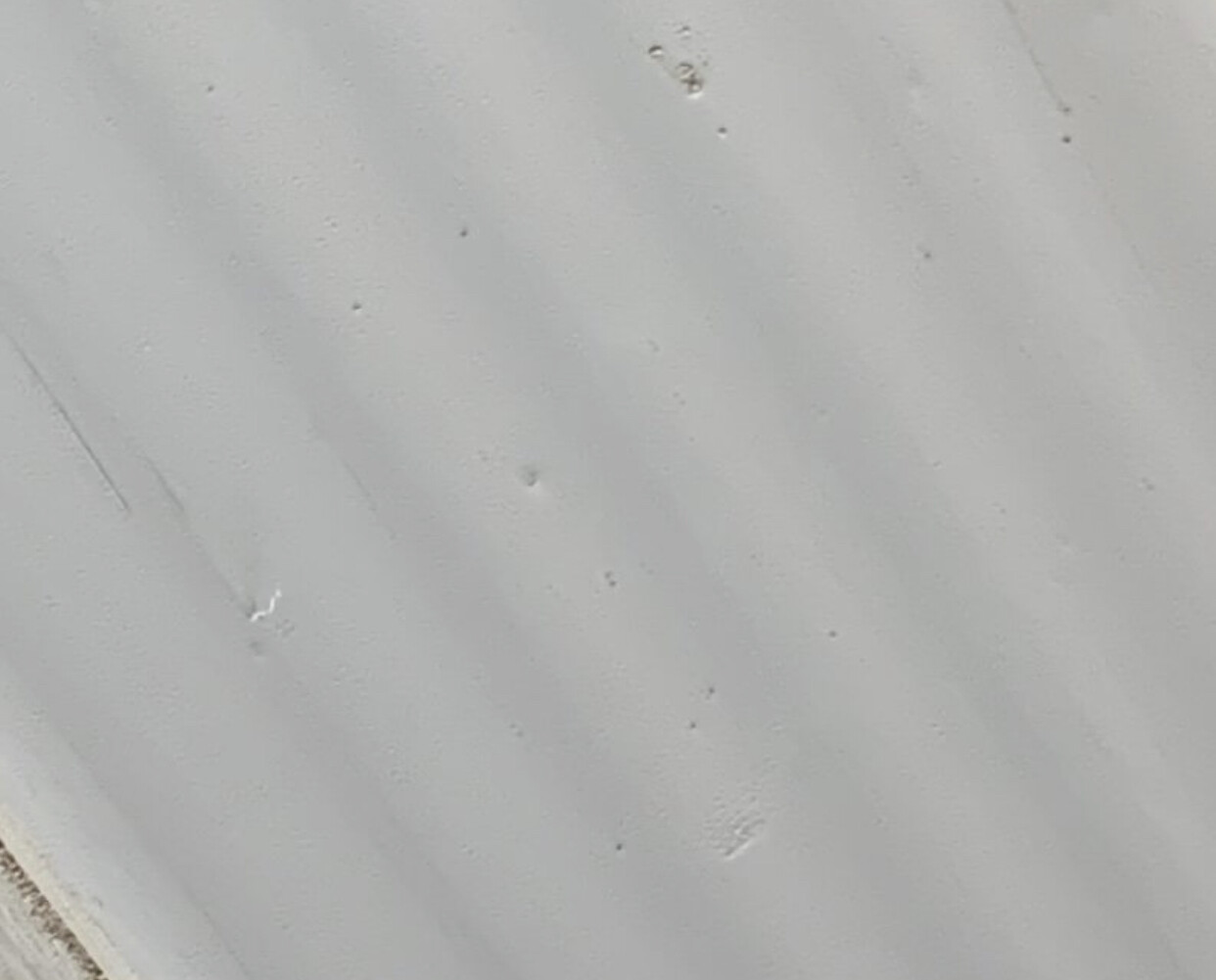 Heller grauer Untergrund mit feinen Kratzern und kleinen Dellen.
