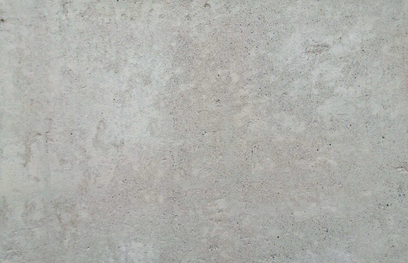 Grau strukturierte Betonoberfläche mit Flecken und Körnung.