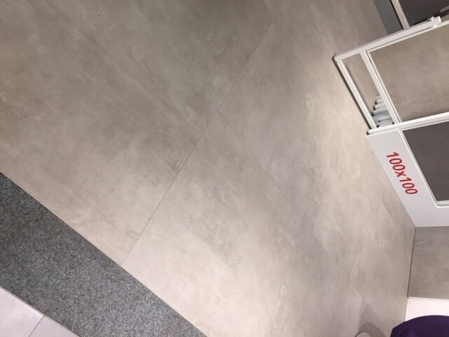 Grosse graue Bodenfliesen im Innenraum, heller Bodenbelag sichtbar