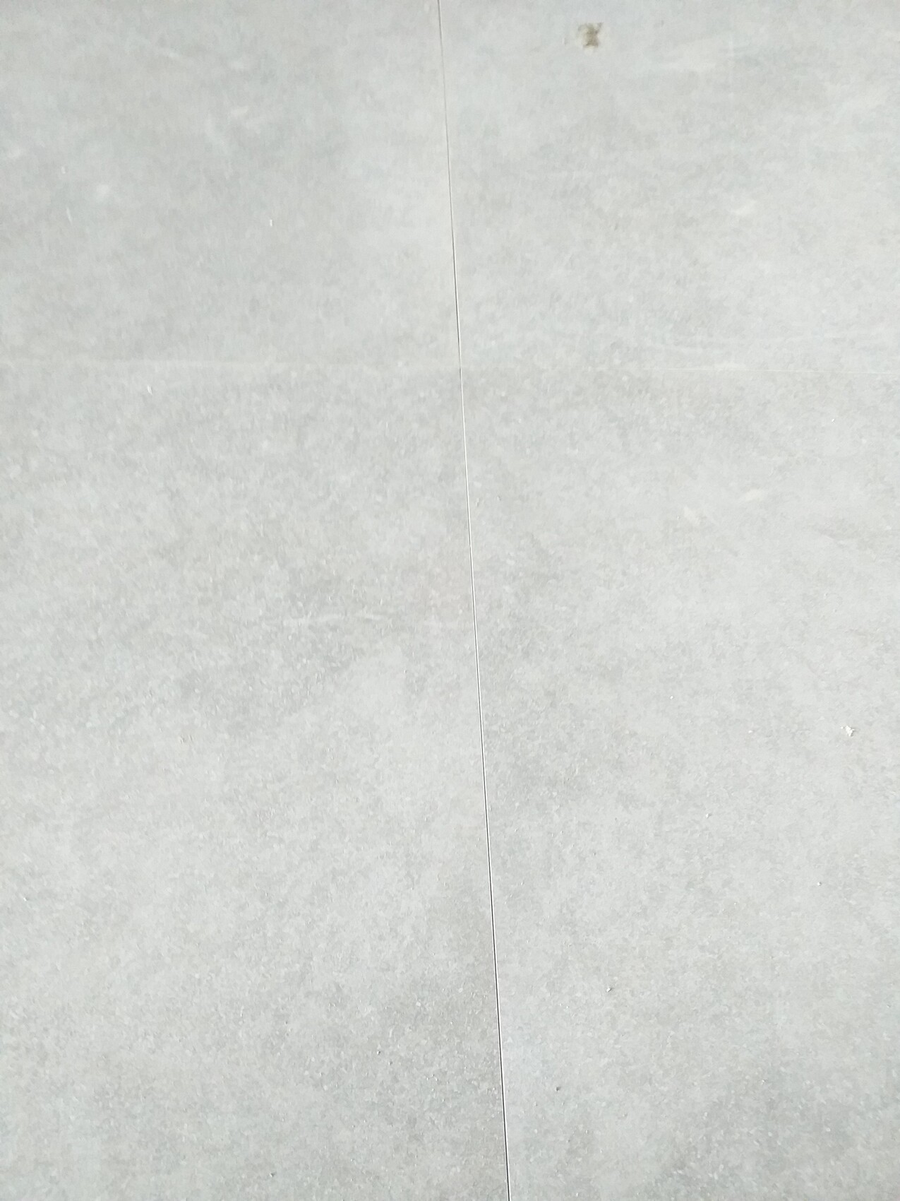 Grau verlegter Beton- oder Steinboden mit senkrechter Fuge in der Mitte.