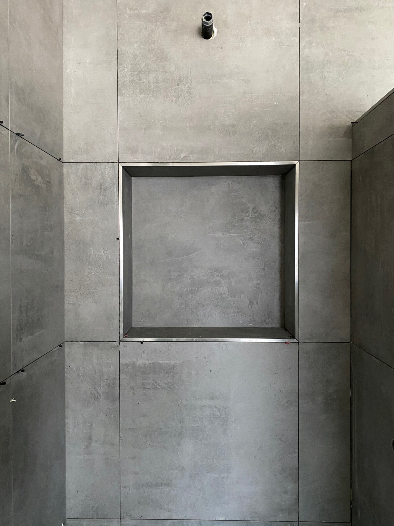 Grau betonoptische Wand mit quadratischer Nische im Metallrahmen
