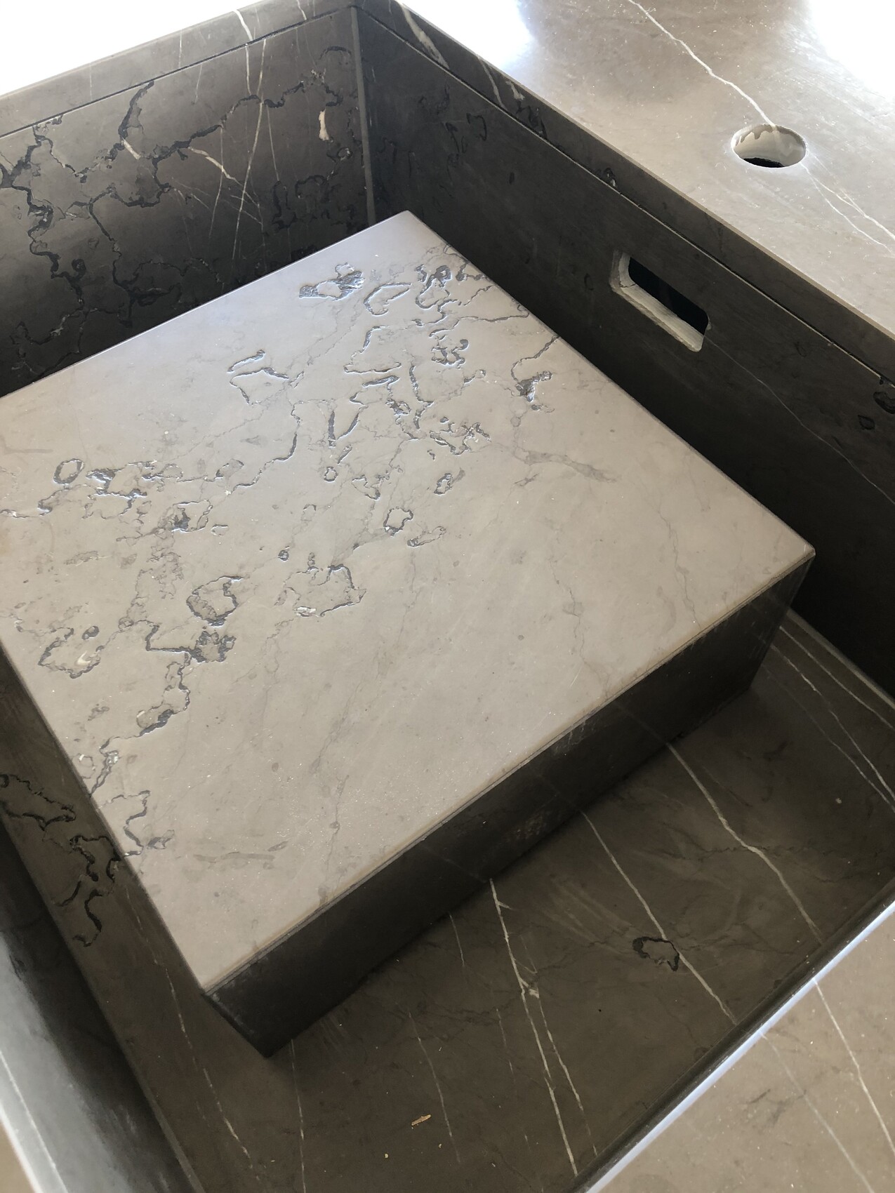 Eckbereich aus dunklem Marmor, darauf eine hellgraue Platte mit Maserung.