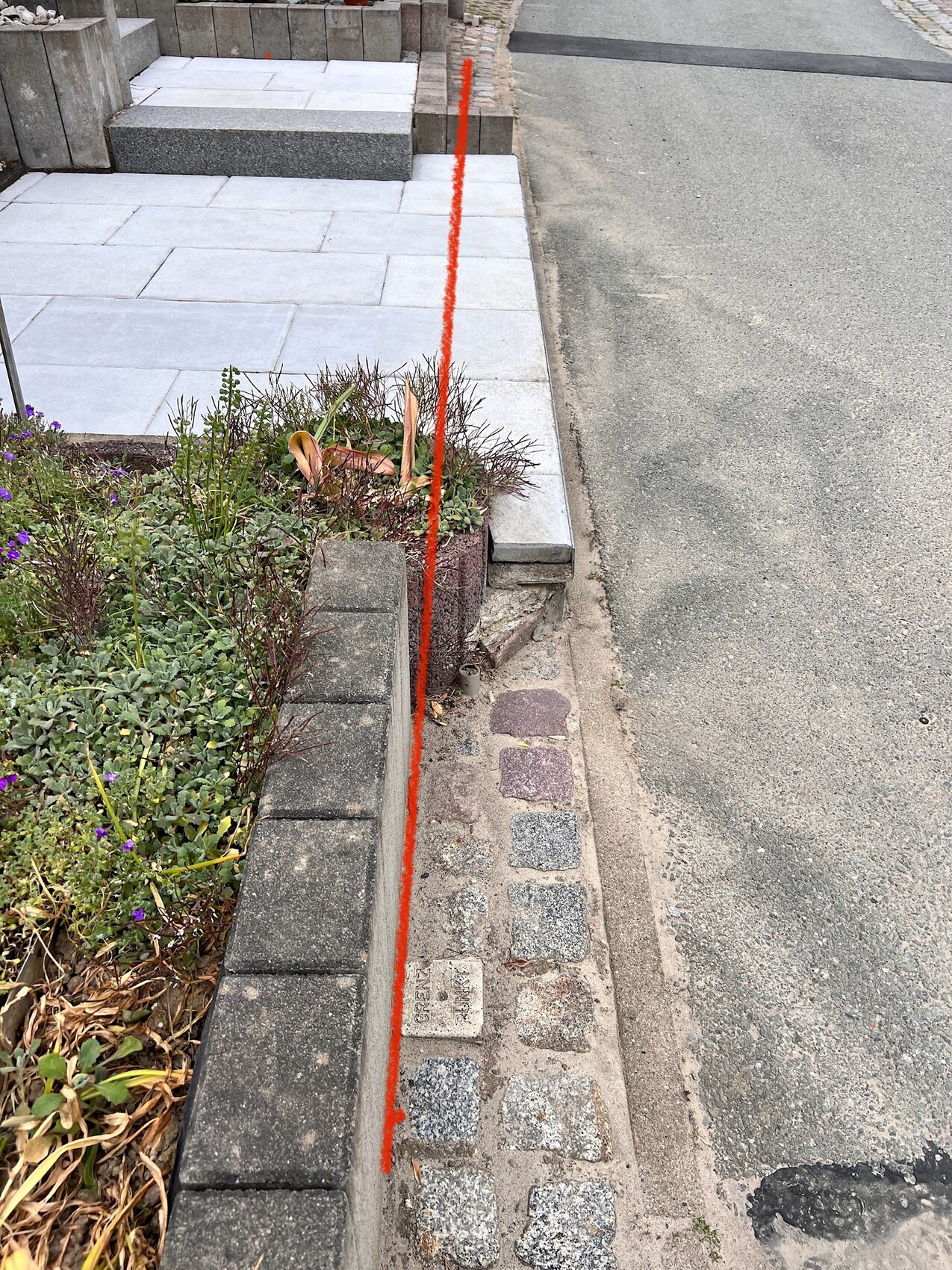 Gehweg neben einem Pflanzbeet; eine rote Linie markiert die Beetsekante.