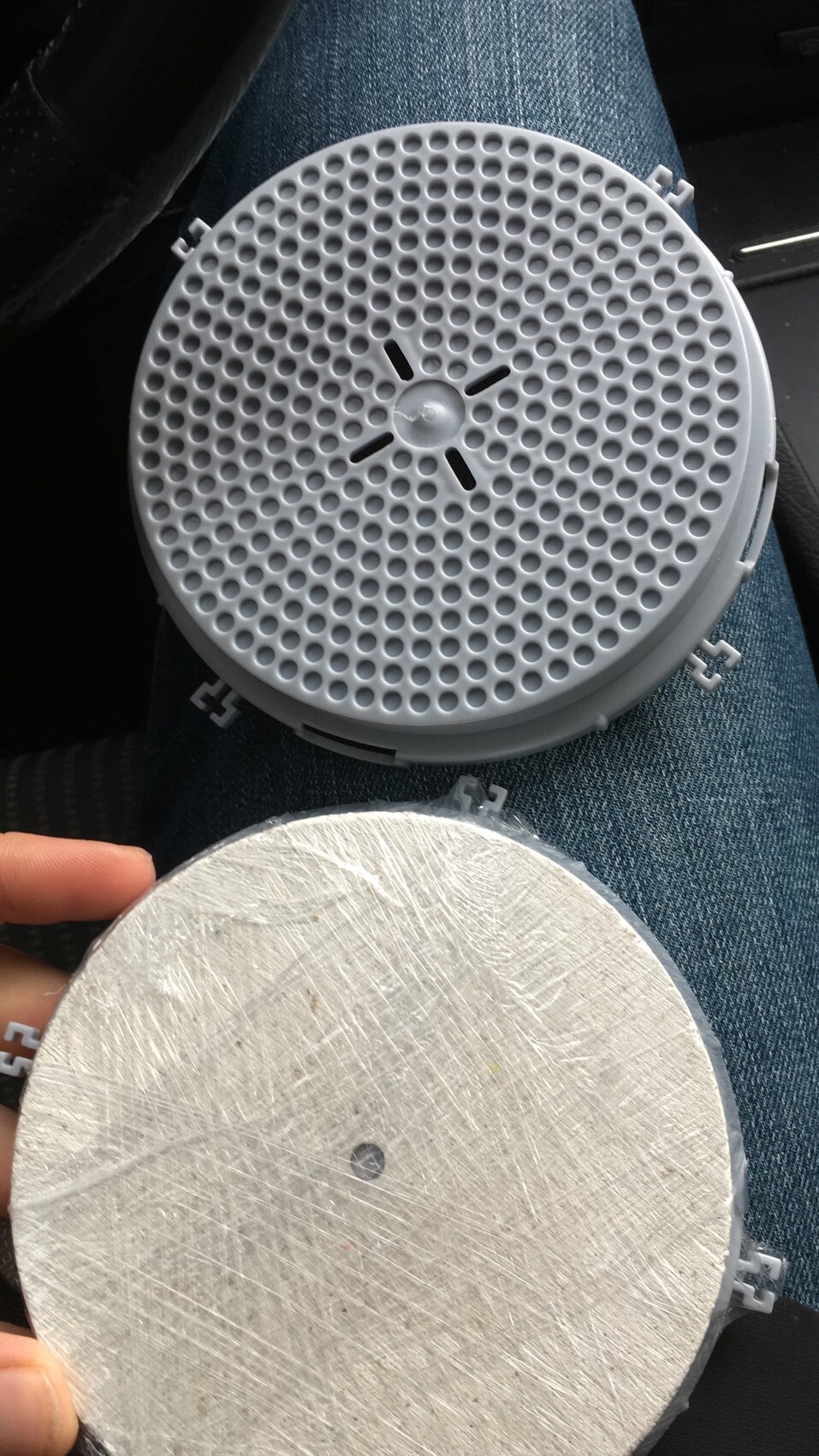 Zwei runde Bauteile: obere graue Lautsprecherabdeckung mit Lochmuster, unten glatte Metallplatte.