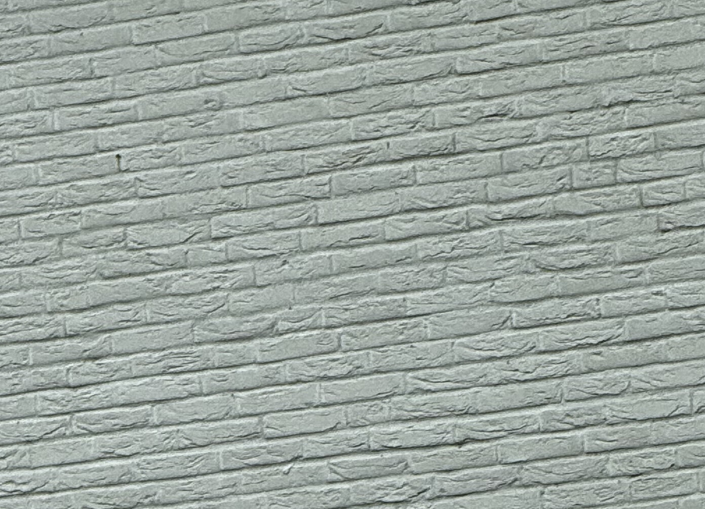 Nahaufnahme einer grauen Steinwand mit unregelmäßigen, flachen Steinplatten und Textur.