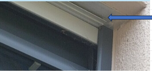 Detailaufnahme eines grauen Fensterrahmens mit Dichtung an der Außenwand