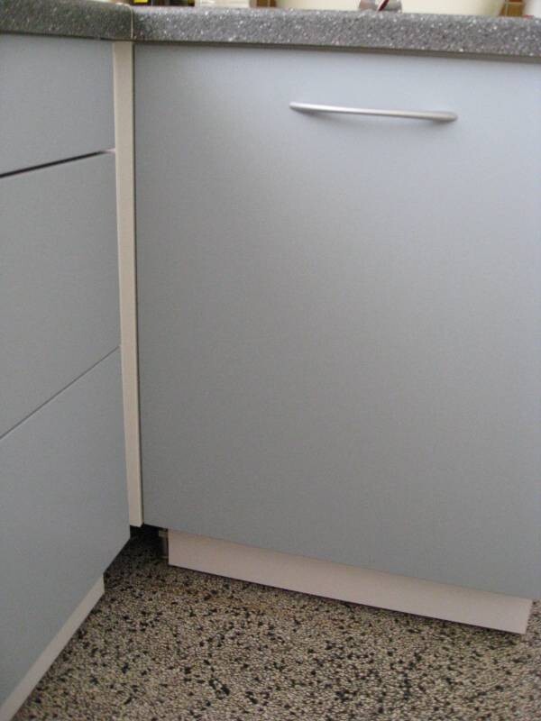 Unterer grauer Küchenschrank mit Silbergriff neben Schubladen; dunkle Arbeitsplatte, terrazzo Boden