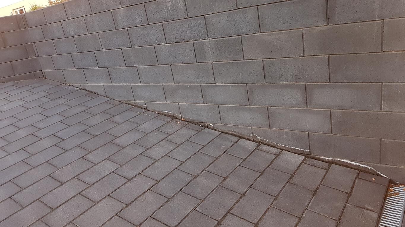 Graues Dach mit Betonsteinwand, Regenrinne am Dachrand – Blick über das Dach.