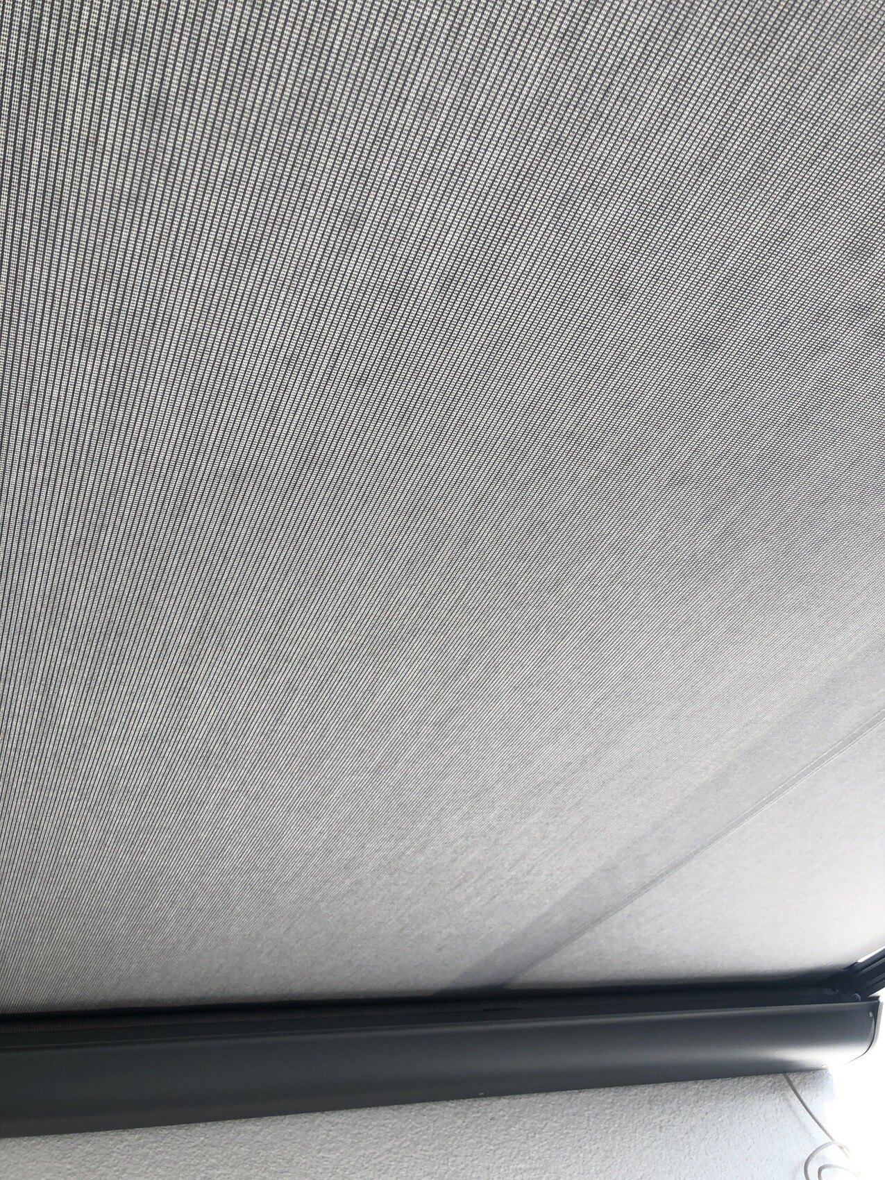 Nahaufnahme eines grauen Fensterrollo-Stoffmusters im Auto