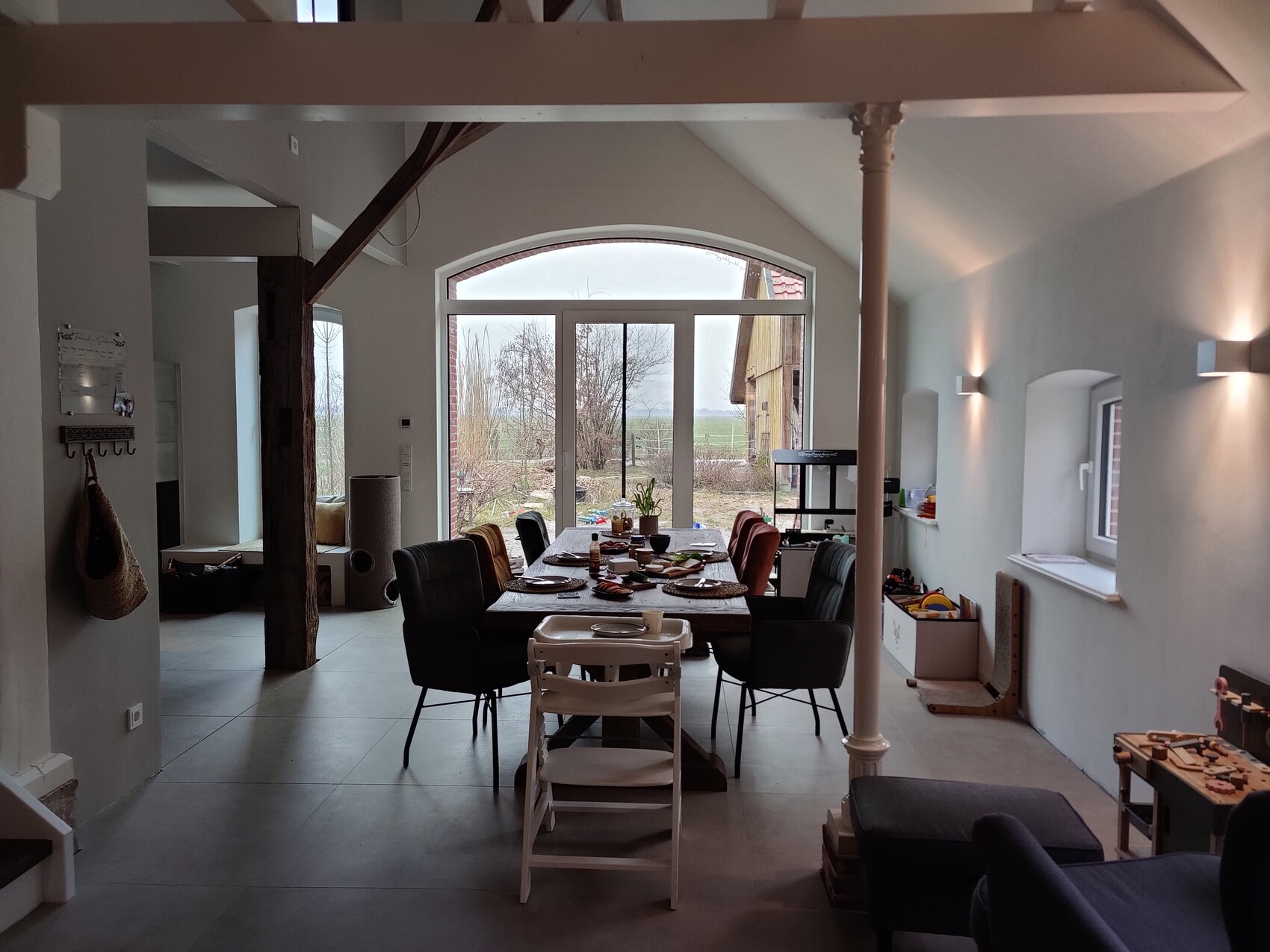 Helles Esszimmer mit langem Tisch, Stühlen und Blick nach draußen durch große Fensterfront.