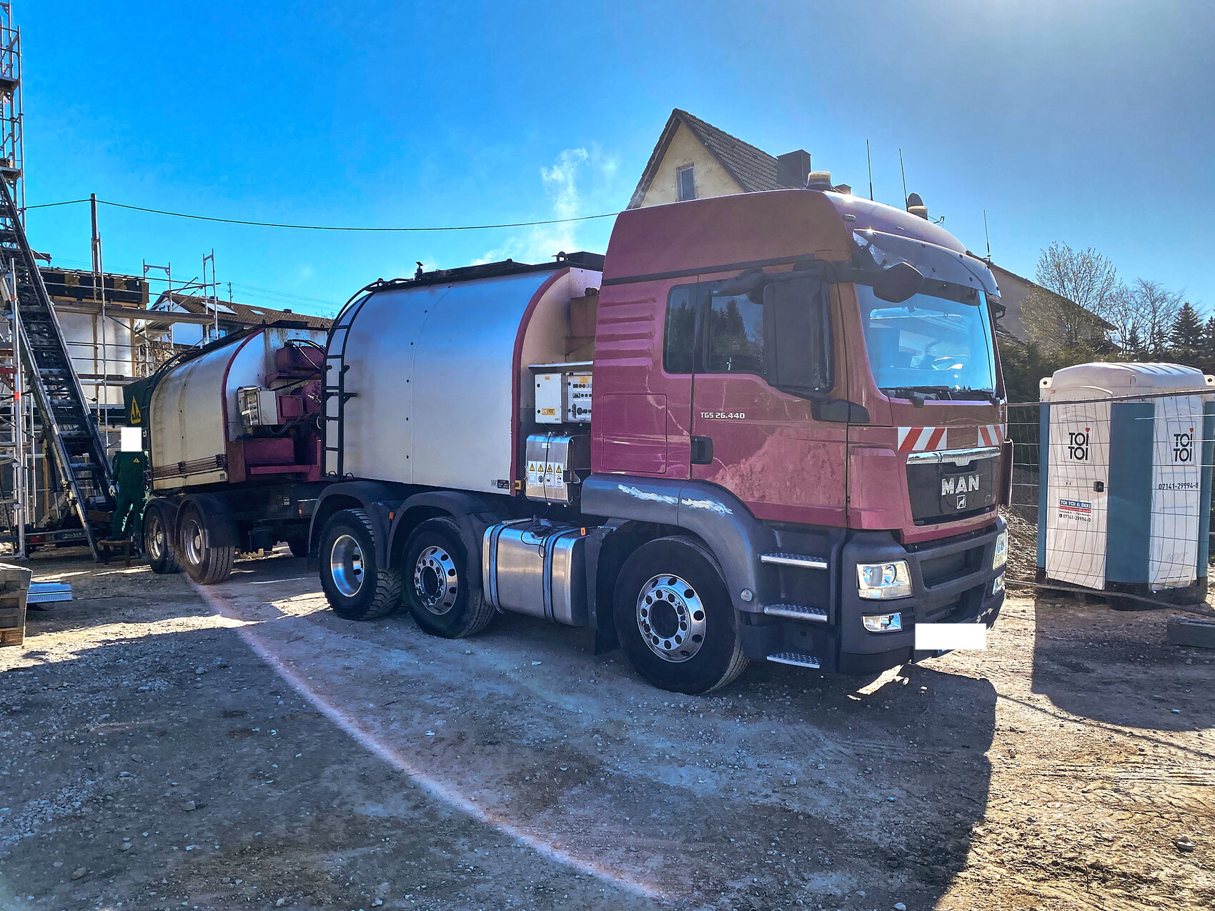 Groesser pinker Betonmischer-LKW steht auf einer Baustelle neben Geruesten